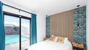 Un dormitorio con una cama grande, vista a una piscina y una puerta corrediza de cristal.