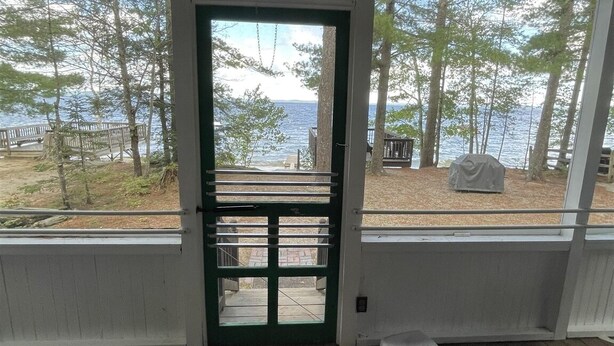 Eine überdachte Veranda mit Blick auf einen See und Bäume.
