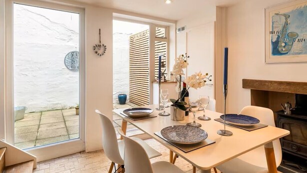 A dining area with a table set for two, a fireplace, and a view of the outside. - Beautiful Townhouse in Brighton's Regency Conservation Area (Brighton and Hove)