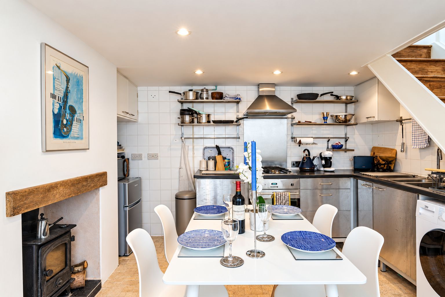 A modern kitchen with white cabinetry, a built-in stove, and a dining area with a white table and chairs.