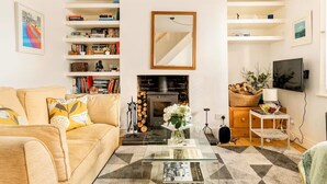 A living room with a sofa, coffee table, fireplace, bookshelves, and a television. - Beautiful Townhouse in Brighton's Regency Conservation Area (Brighton and Hove)