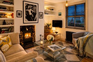 Uma sala de estar aconchegante com lareira, sofá, mesa de centro e televisão.