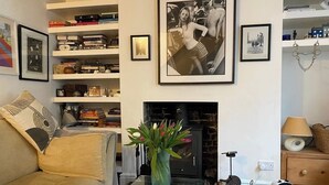 A living room with a sofa, a coffee table with a book, a fireplace, a bookshelf, and framed pictures on the wall. - Characterful Brighton Townhouse, One Minute from the Beach (Brighton and Hove)