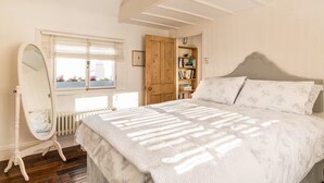 A bedroom with a large bed, a wooden wardrobe, a mirror, and a window with blinds. - Beautiful Townhouse in Brighton's Regency Conservation Area (Brighton and Hove)