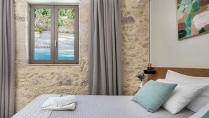 Ein Schlafzimmer mit Steinwand, einem Vorhangfenster, einem Bett mit Kissen und einem Bild an der Wand.