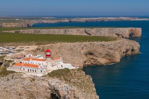 A coastal building with a red-roofed tower, situated on a rocky cliff overlooking the sea. - New, Nature View - Albufeira, Private Pool (Albufeira)