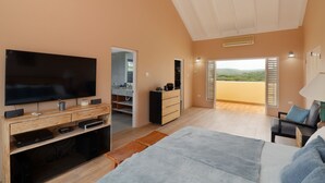 Une chambre moderne dotée d’une grande télévision, de meubles en bois, d’un lit et d’un balcon avec vue.