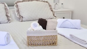 A neatly made bed with pillows, a bedside table with a lamp, and a small basket with toiletries. - Golden Moon, Ponta do Sol - Canhas (Funchal)