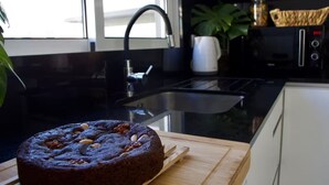 A kitchen with a cake on a wooden board, a sink, a microwave, and a plant. - Golden Moon, Ponta do Sol - Canhas (Funchal)