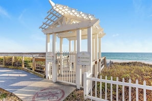 A white wooden gazebo with a sign indicating it's a private beach resort.