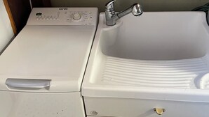 A compact laundry room with a washing machine, a sink, and a small storage cabinet. - Delux-The Terrace Over The Marine Park (Quartu Sant'Elena)