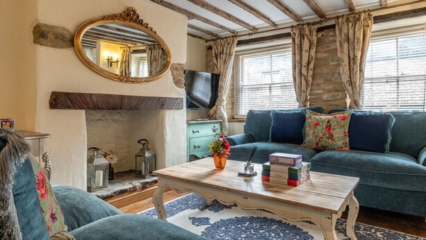 A cozy living room with a blue sofa, a wooden coffee table, and a fireplace. - Eilmers Cottage - Beautiful 4BD in Malmesbury (Malmesbury)