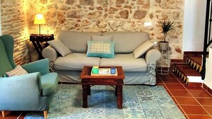 Una sala de estar con pared de piedra, un sofá, una silla, una mesa de centro y una lámpara.