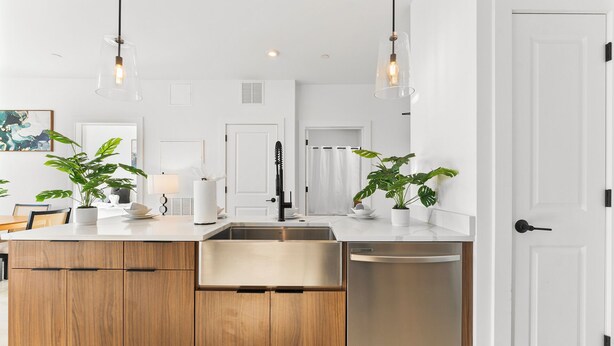A modern kitchen with wooden cabinets, stainless steel appliances, and pendant lighting.
