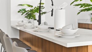 A modern kitchen with a white countertop, grey chairs, and a wooden cabinet.