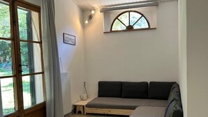 A room with a bed, a small table, a window, and a radiator. - B&B "Il Melograno" cottage with private pool in Pistoia. (Pistoia)