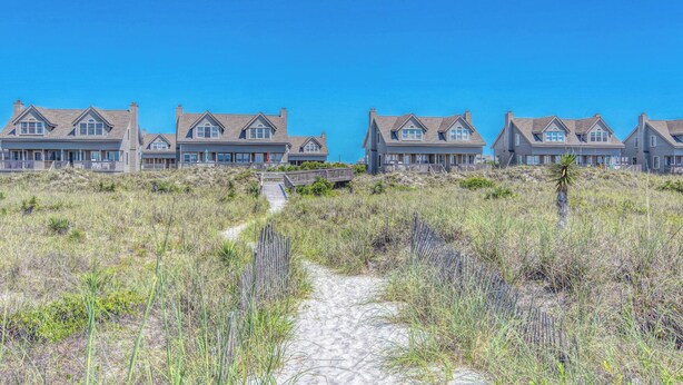 A beachfront property with a sandy path leading to a row of houses.