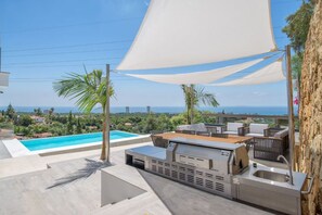 An outdoor patio with a pool, a grill, and a view of the ocean. - Sunrise Villa Marbella by Lodgerstrip (Marbella)