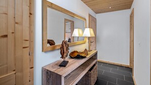 Ein Flur mit Holzboden, einem großen Spiegel, einem Holzkonsolentisch mit einer Lampe und einem Korb.