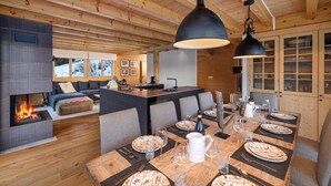 Ein gemütliches Blockhaus-Interieur mit Essbereich, gedecktem Tisch, Kamin und Küchenzeile.