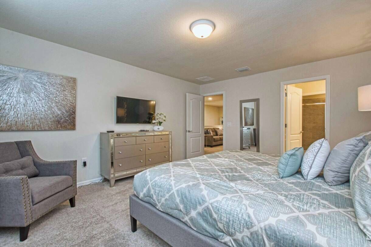 Une chambre à coucher avec un lit, une commode, une chaise et un tableau accroché au mur.