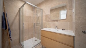 Ein modernes Badezimmer mit einer Duschkabine aus Glas, einem weißen Waschbecken und einer Holzausstattung.