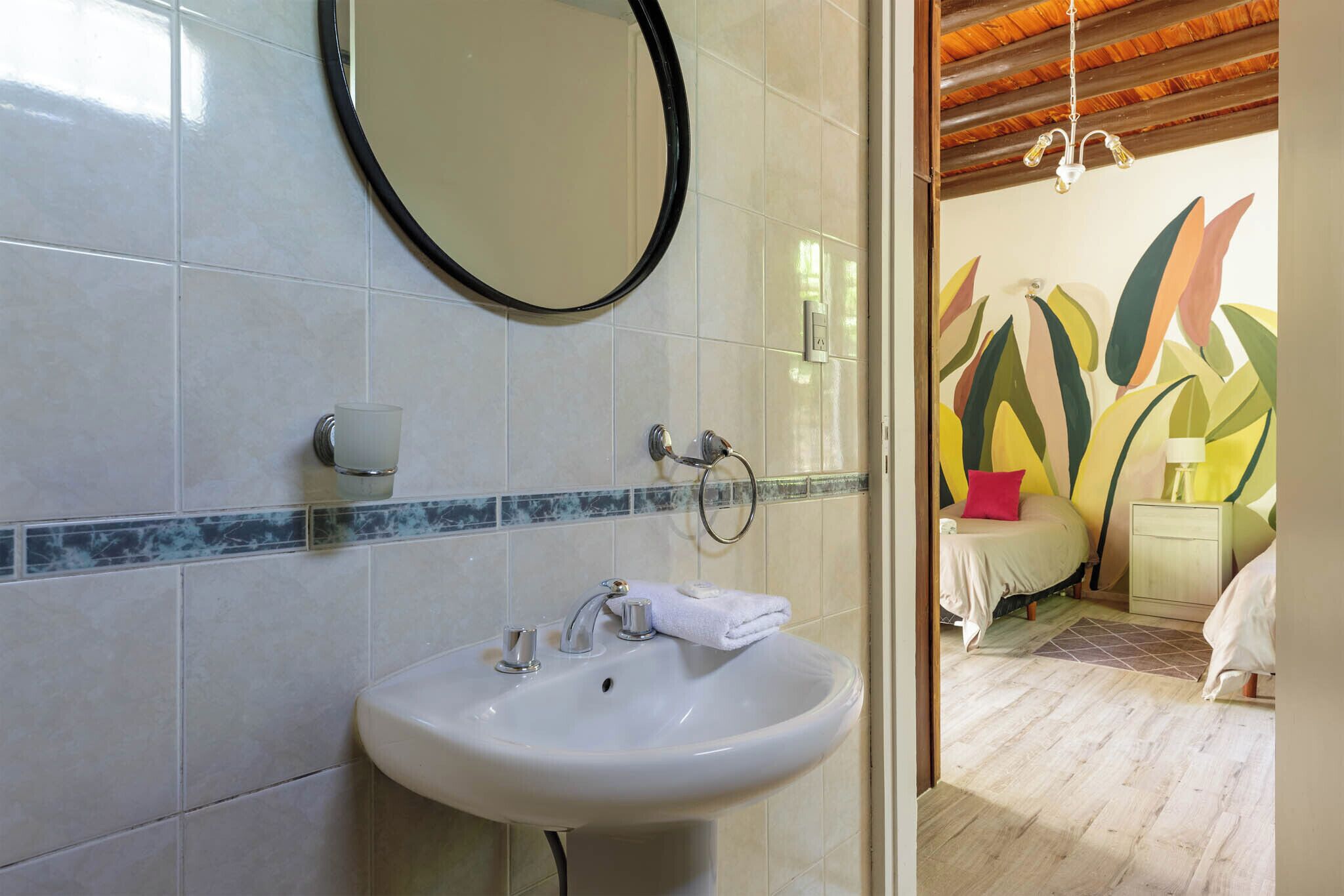 A bathroom with a white sink, a round mirror, and a towel rack.