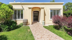 A two-story house with a tiled entrance walkway, a garage door, and a small porch area. - MOT Besares (Chacras de Coria)