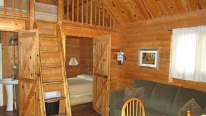 A wooden cabin interior with a loft bedroom, a dining area, and a living room with a sofa and chairs. - Charming cabin 25 with 1 bedroom and Wi-Fi, fitness room, Pool in fabulous Mayo (Mayo)