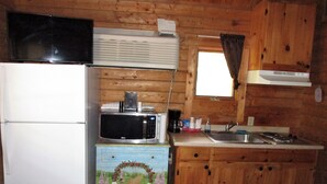 A compact kitchen with wooden walls, a refrigerator, a microwave, a coffee maker, and a sink. - Charming cabin 25 with 1 bedroom and Wi-Fi, fitness room, Pool in fabulous Mayo (Mayo)