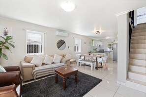 Relax in this stylish living space with a comfortable sofa, dining area, and modern kitchen.