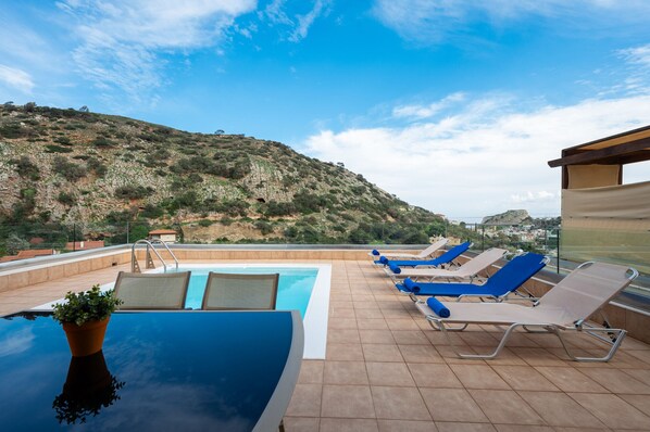 Zona de piscina en la azotea con sillones y vistas a un paisaje montañoso.