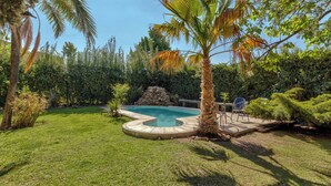 A backyard with a swimming pool, surrounded by lush greenery and palm trees. - MOT Alzaga (Chacras de Coria)