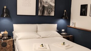 Une chambre à coucher bien rangée, avec un lit, des tables de chevet et des œuvres d’art accrochées au mur.