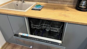 Een keuken met een vaatwasser, een spoelbak en een koffiezetapparaat op het aanrecht.