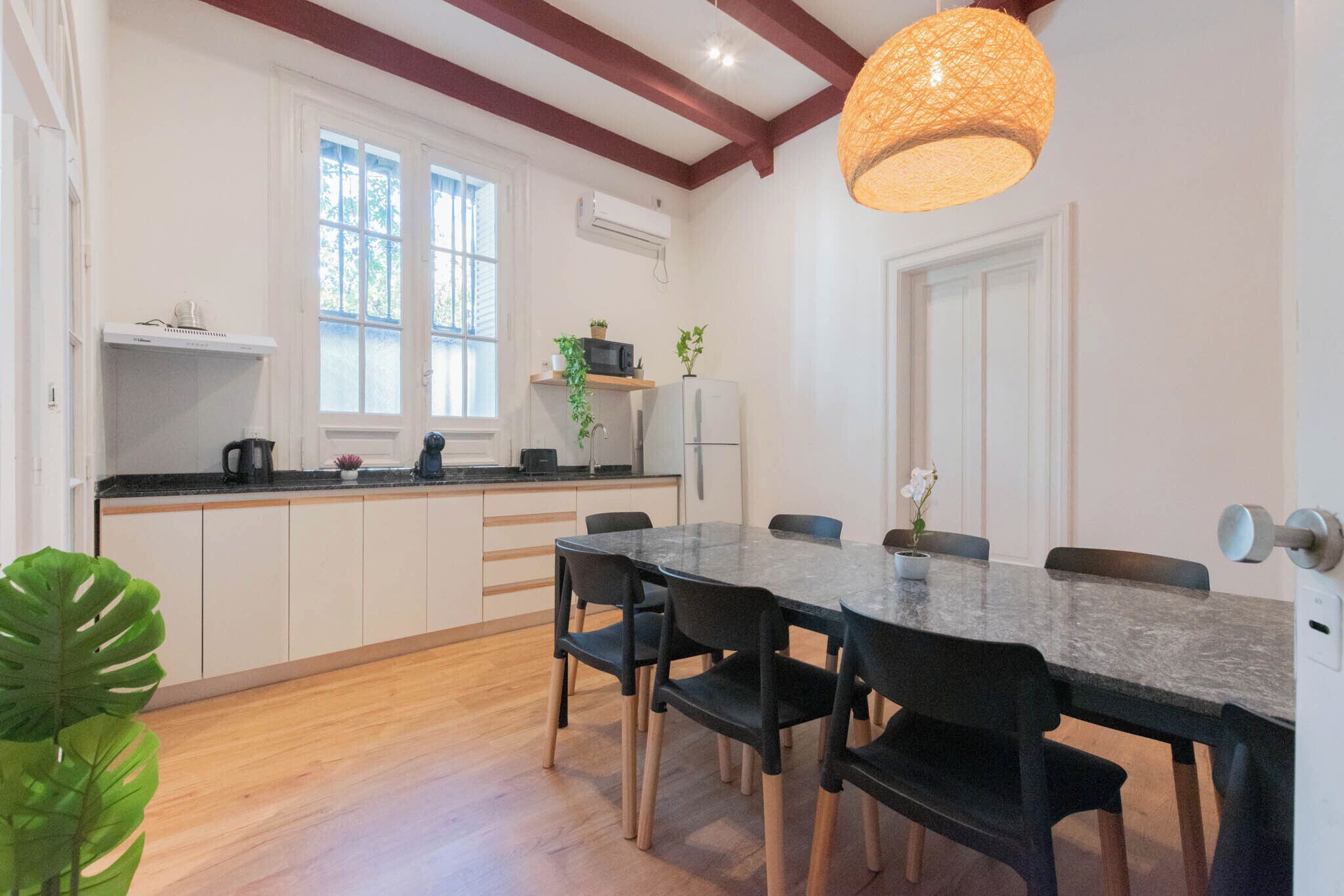 Una cocina moderna con armarios blancos, encimera negra y una mesa de comedor con sillas.