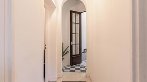 A hallway with a checkered floor, a door with glass panels, and a plant near the door. - MOT Mansion Paz (Buenos Aires)