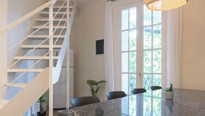 A modern interior with a staircase, a dining area with a marble table, and large windows. - MOT Mansion Paz (Buenos Aires)