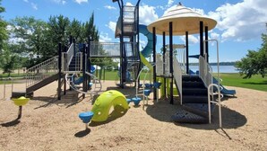 Un parque infantil con tobogán, estructuras para escalar y una zona cubierta.