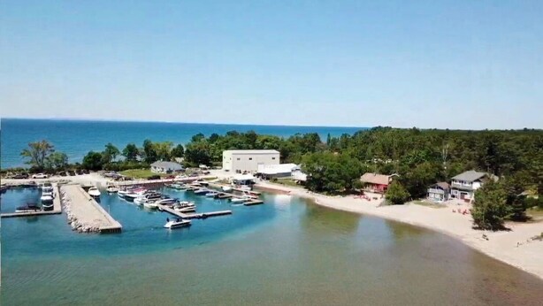 Un puerto deportivo con barcos amarrados, una playa de arena y edificios al fondo.