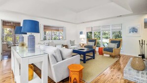 A spacious living room with a white sofa, blue and white lamps, and a large window.