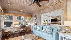 A cozy room with a light blue sofa, a round coffee table, a wooden ceiling fan, and a large mirror.