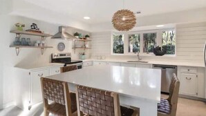 A modern kitchen with white cabinetry, a large island, and a hanging light fixture.