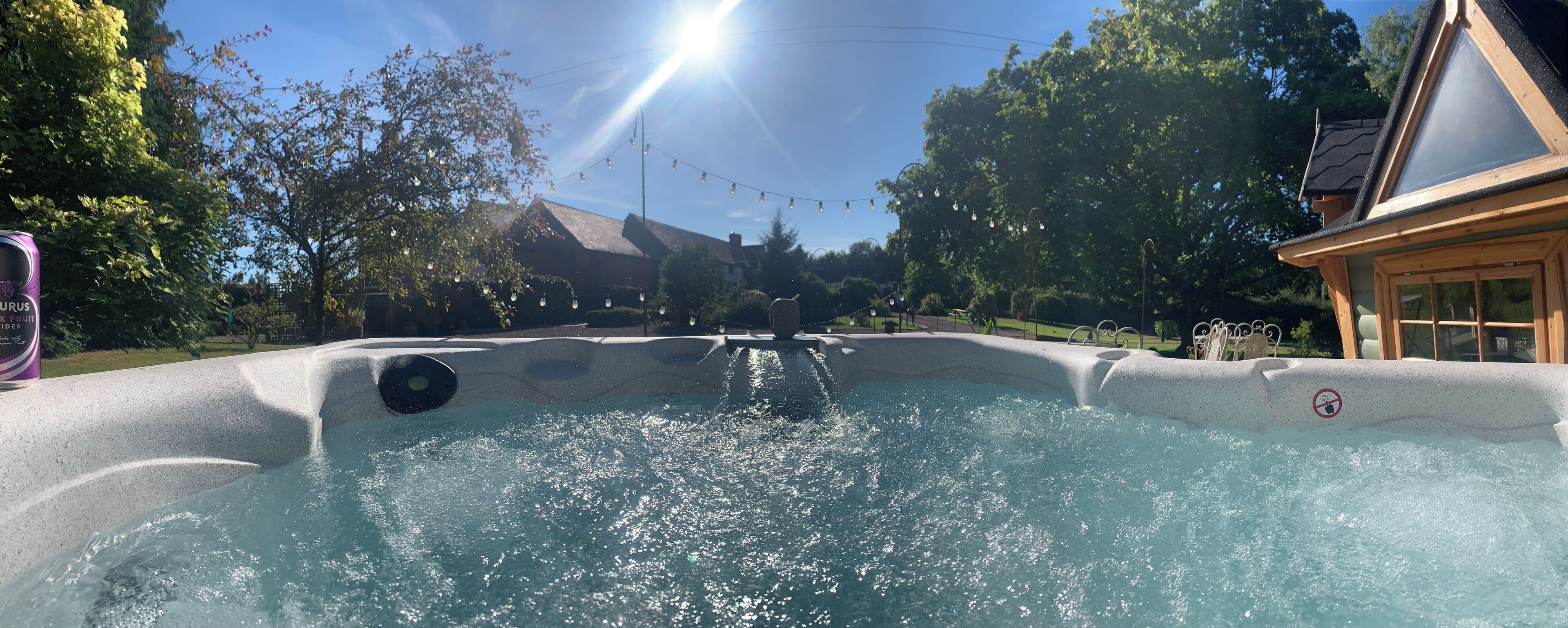 A hot tub with a no-entry sign, surrounded by trees and a house.
