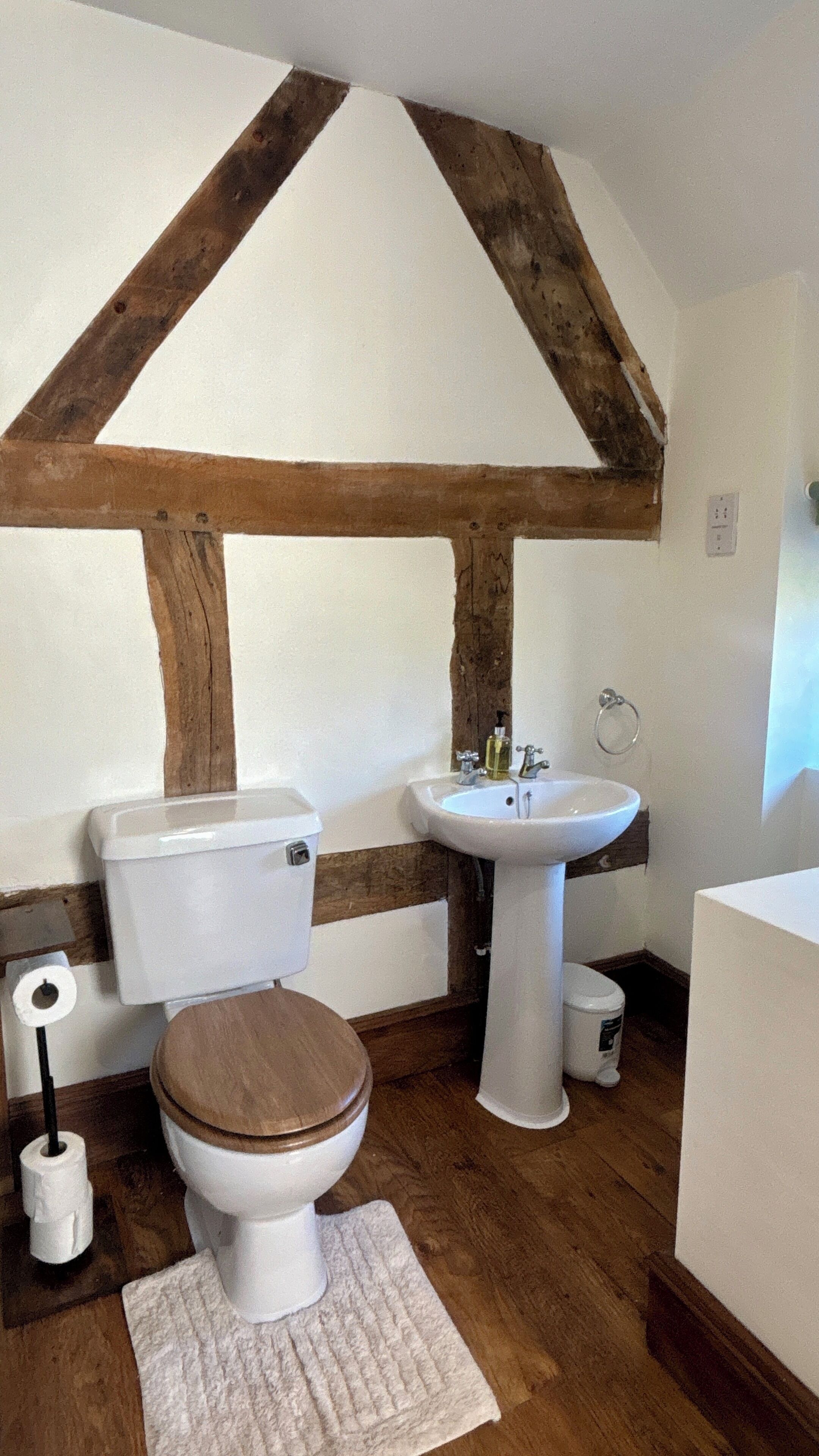 A bathroom with a white toilet, wooden vanity, and a sink.