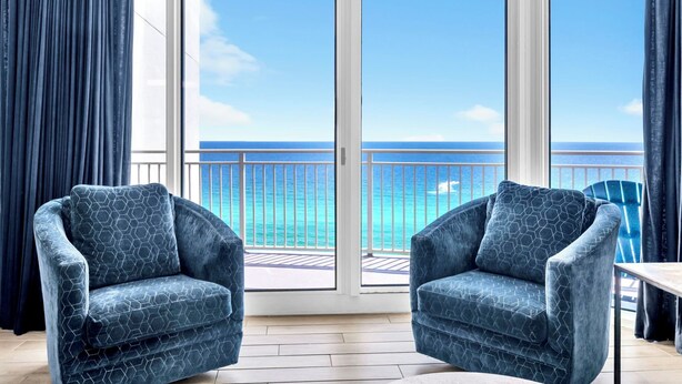 Un balcon avec vue sur l’océan, deux fauteuils et une table.