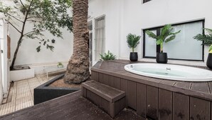 A modern outdoor spa area with a wooden deck, a hot tub, and potted plants. - MOT Villa Embajada (Buenos Aires)