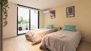 A hotel room with two beds, a sliding glass door to the outside, and a ceiling light. - MOT Villa Embajada (Buenos Aires)