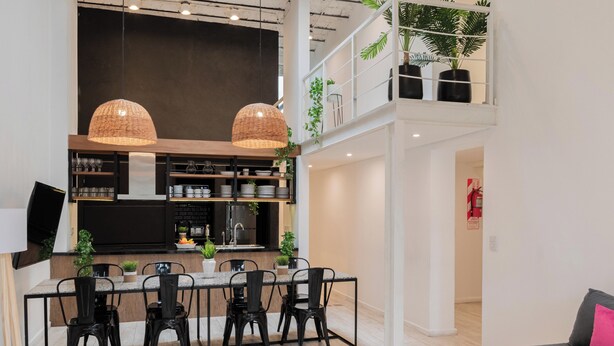 A modern kitchen with a dining area, featuring a large island, black chairs, and pendant lights. - MOT Villa Embajada (Buenos Aires)
