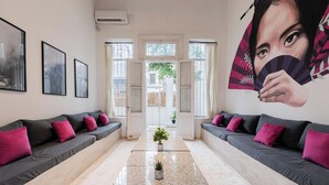 A modern lobby with a central plant, two sofas with cushions, framed artwork on the walls, and a large mural. - MOT Villa Embajada (Buenos Aires)